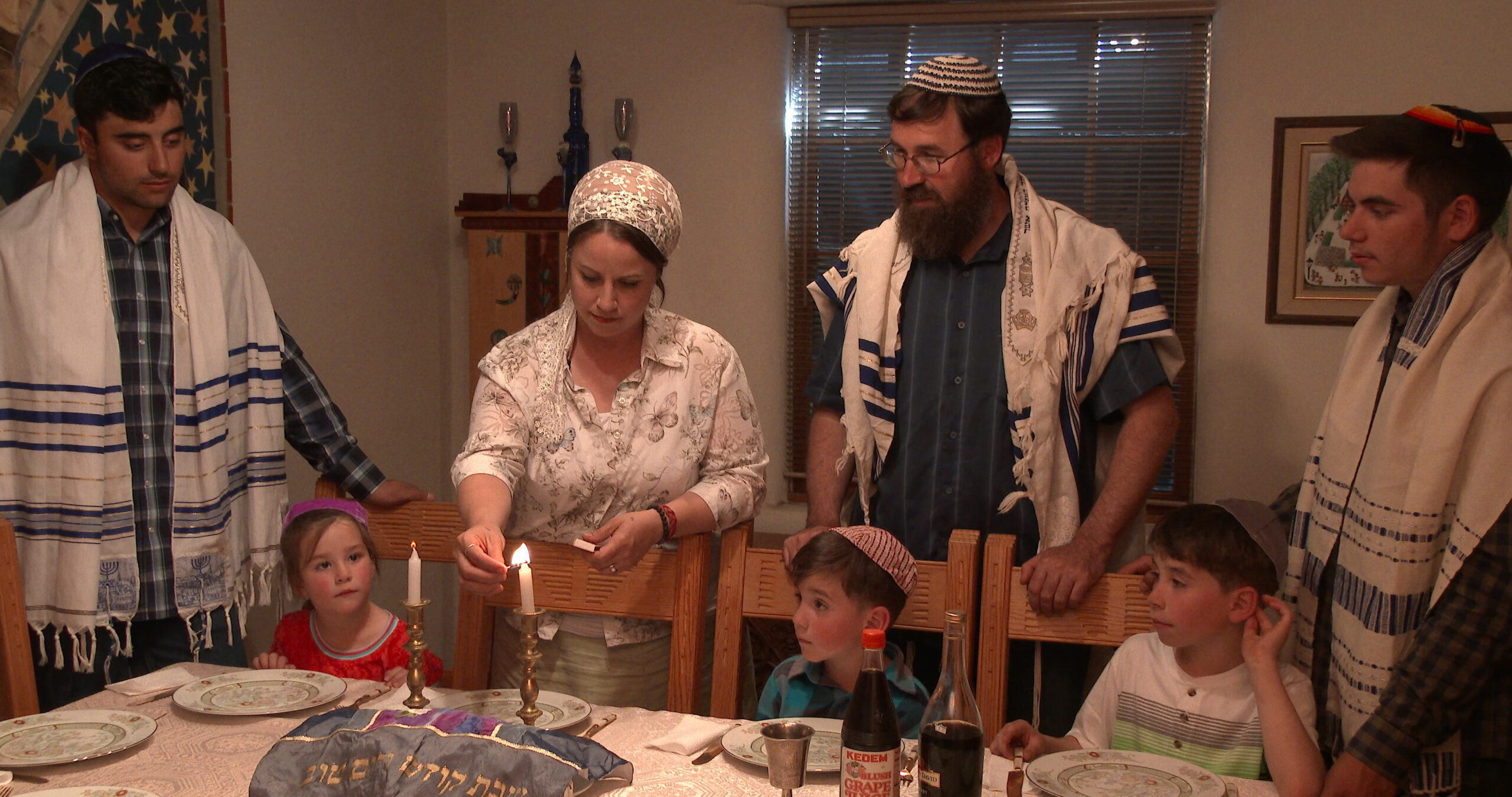 A Jewish family stands around a table.