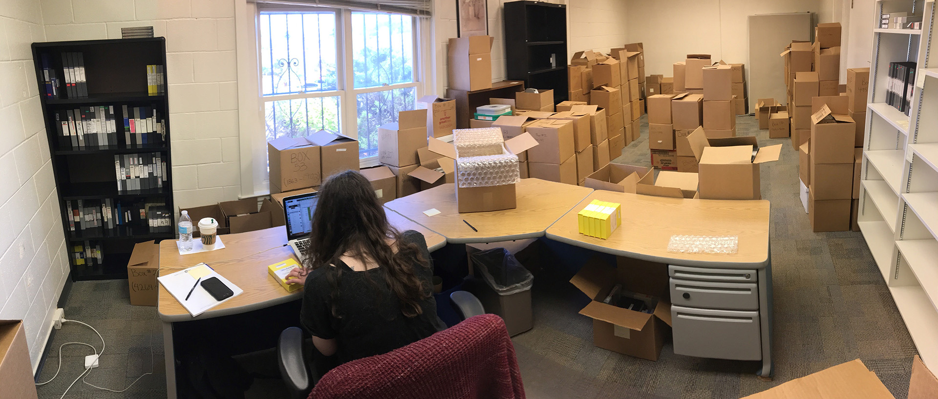 Archivist Megan Rose works at a desk to process boxes of media.