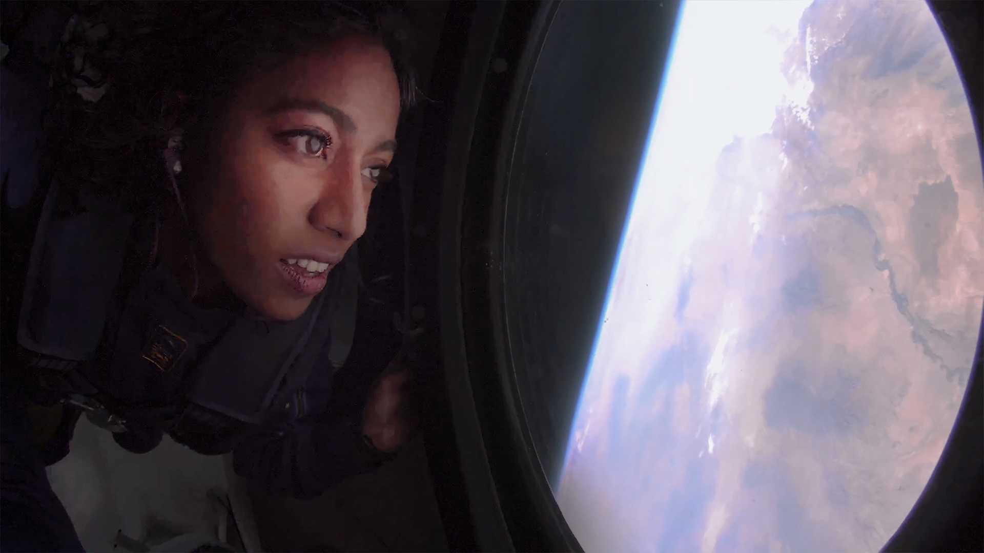 A woman looks out a window at Earth from the Virgin Galactic
